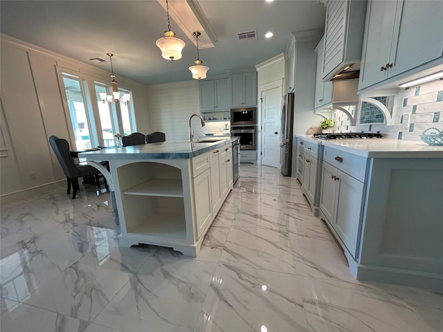 kitchen with tasteful backsplash, an island with sink, hanging light fixtures, and appliances with stainless steel finishes