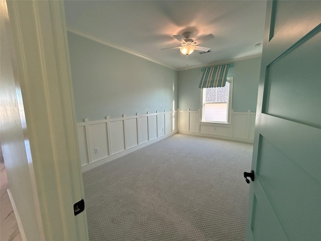 carpeted spare room featuring ceiling fan and ornamental molding