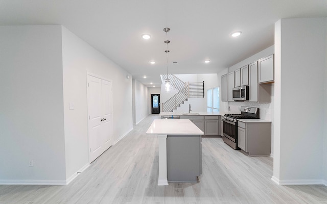 kitchen with sink, a center island, pendant lighting, gray cabinets, and appliances with stainless steel finishes