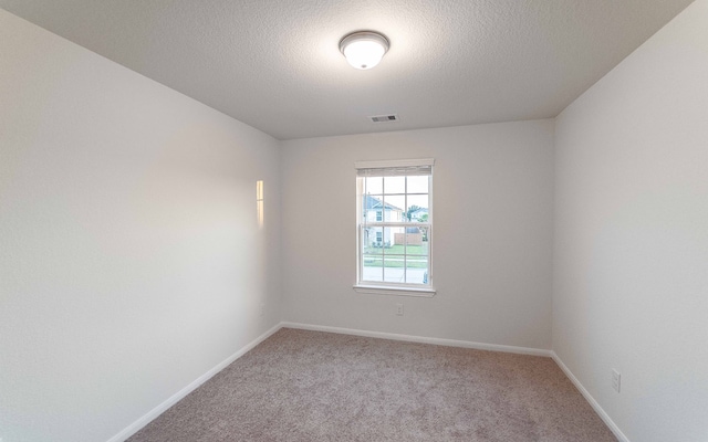 carpeted empty room featuring a textured ceiling