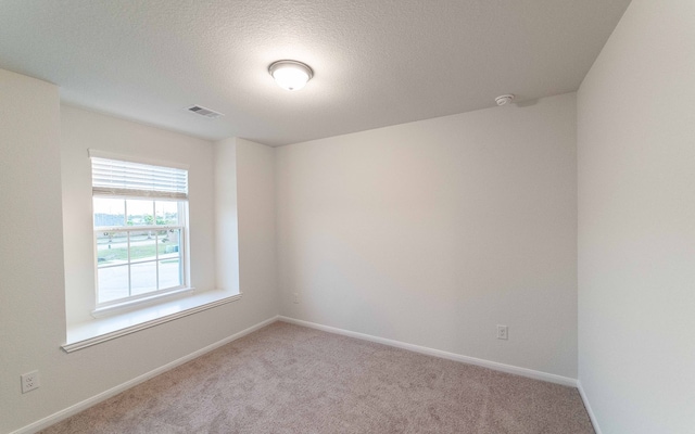 carpeted empty room featuring a textured ceiling