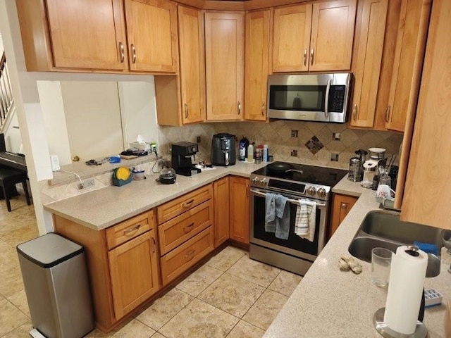 kitchen with light tile patterned floors, backsplash, stainless steel appliances, and sink