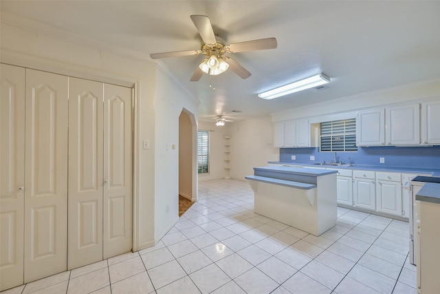 102 N Noble Rd, Texas City, TX 77591 - kitchen featuring a ceiling fan, a sink, arched walkways, white cabinetry, and light tile patterned floors