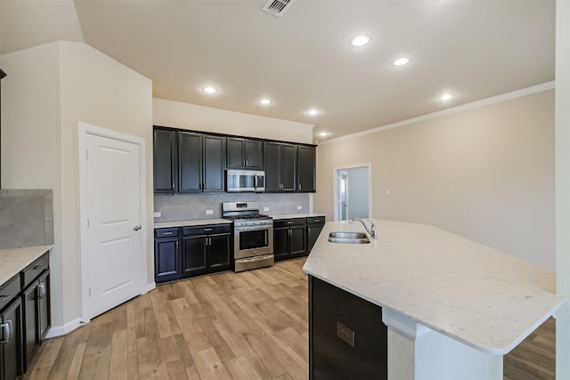 kitchen featuring appliances with stainless steel finishes, light hardwood / wood-style flooring, and a kitchen island with sink