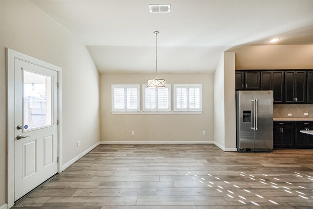 kitchen with pendant lighting, stainless steel refrigerator with ice dispenser, a wealth of natural light, and vaulted ceiling