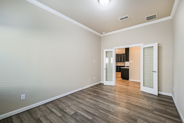 empty room featuring crown molding, french doors, and hardwood / wood-style floors