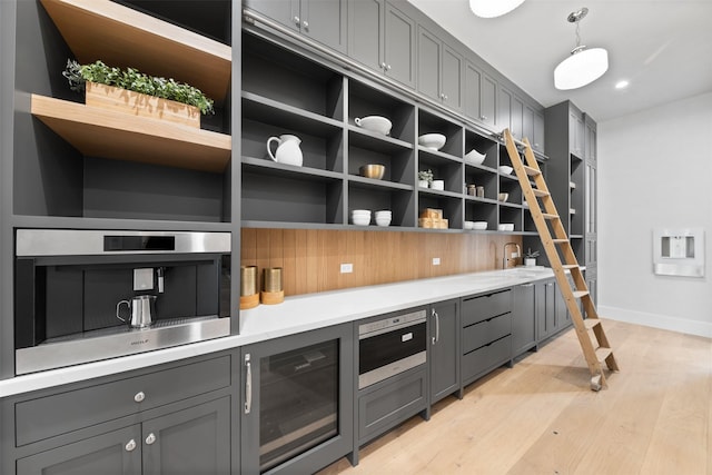 kitchen with gray cabinetry, beverage cooler, and decorative light fixtures