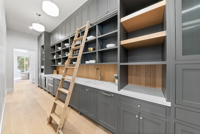 kitchen featuring sink, pendant lighting, gray cabinetry, and light hardwood / wood-style flooring