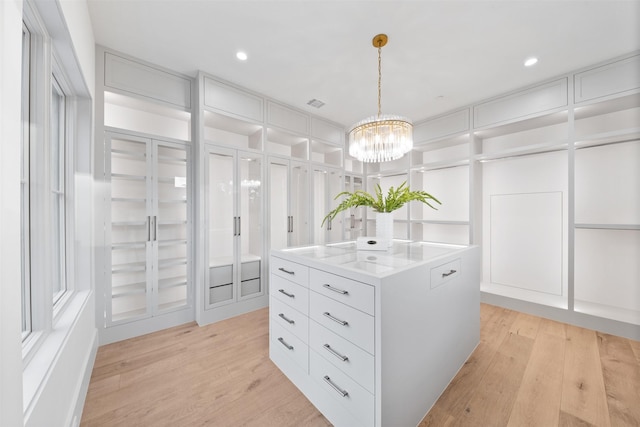 walk in closet featuring an inviting chandelier and light hardwood / wood-style floors