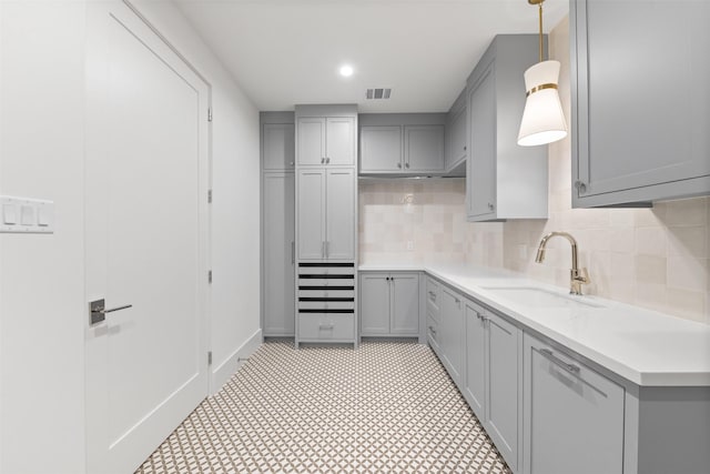 kitchen with sink, backsplash, gray cabinetry, and hanging light fixtures