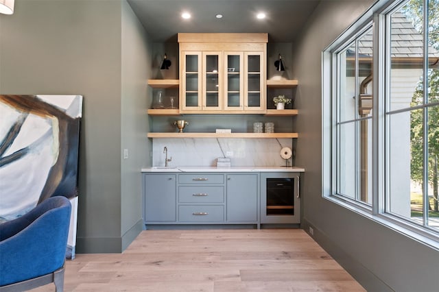 bar featuring wine cooler, gray cabinets, light hardwood / wood-style floors, and sink