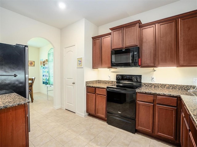 kitchen featuring light stone counters, light tile patterned floors, and black appliances