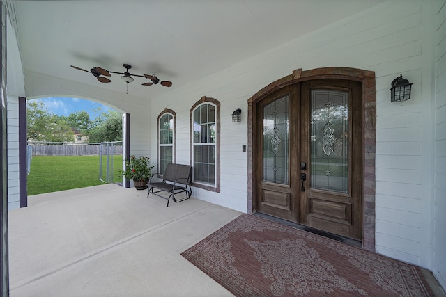 entrance to property with covered porch, french doors, ceiling fan, and a lawn