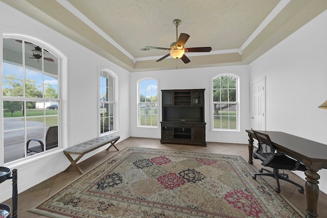 tiled office with a tray ceiling, a wealth of natural light, ceiling fan, and ornamental molding