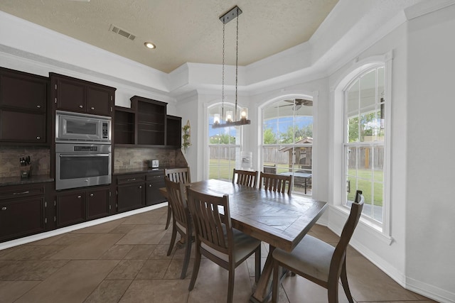 dining area with dark tile patterned floors, a textured ceiling, a wealth of natural light, and ornamental molding