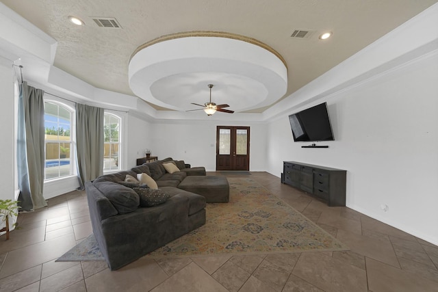 living room with french doors, a tray ceiling, ceiling fan, and a healthy amount of sunlight