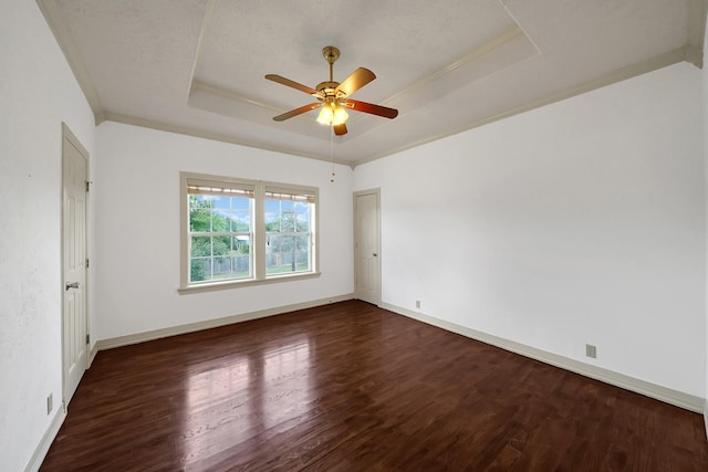 empty room with a textured ceiling, dark hardwood / wood-style floors, ceiling fan, and a tray ceiling