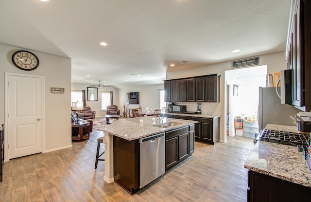 kitchen with appliances with stainless steel finishes, a center island with sink, light hardwood / wood-style flooring, and sink