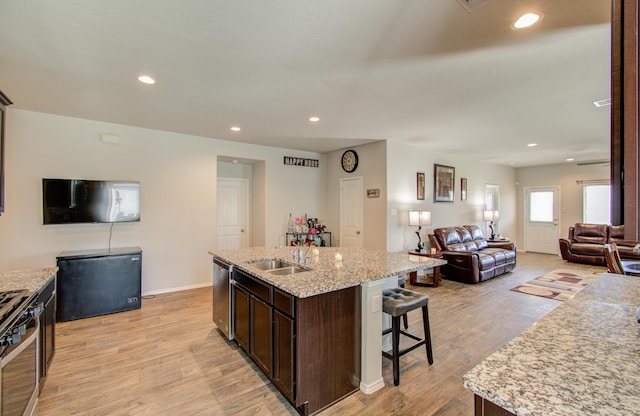 kitchen with a center island with sink, light hardwood / wood-style flooring, stainless steel appliances, and sink