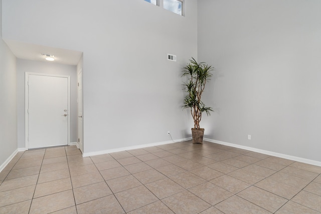 tiled spare room featuring a towering ceiling