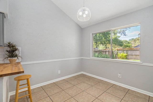 tiled empty room featuring a chandelier and lofted ceiling