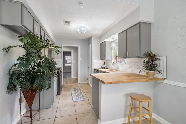 1611 Cantrell Blvd, Conroe, TX 77301 - kitchen featuring gray cabinets, a sink, a textured ceiling, tasteful backsplash, and a breakfast bar