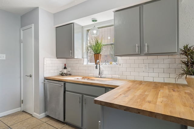 kitchen featuring pendant lighting, dishwasher, gray cabinets, light tile patterned floors, and butcher block countertops