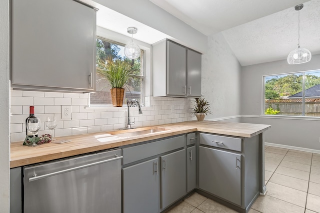 kitchen featuring pendant lighting, dishwasher, gray cabinetry, and wood counters