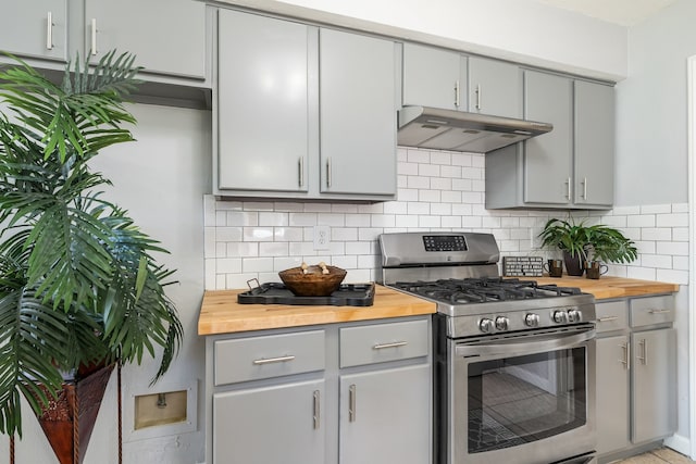 kitchen with gray cabinets, decorative backsplash, stainless steel gas stove, and wooden counters