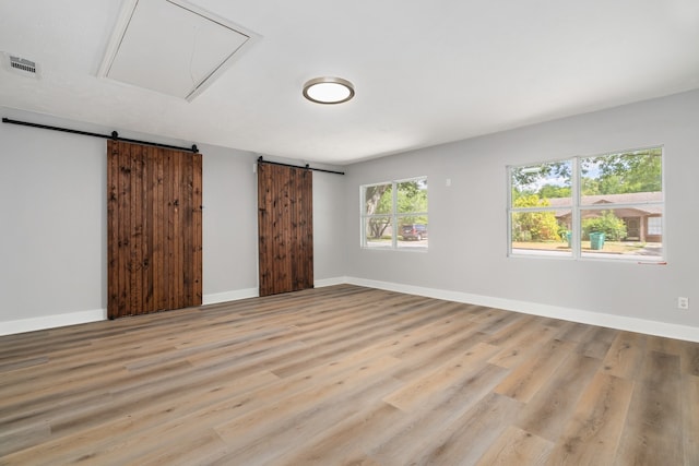 empty room featuring a barn door and light hardwood / wood-style floors