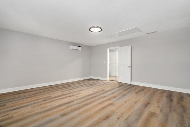 empty room featuring light wood-type flooring and a wall unit AC