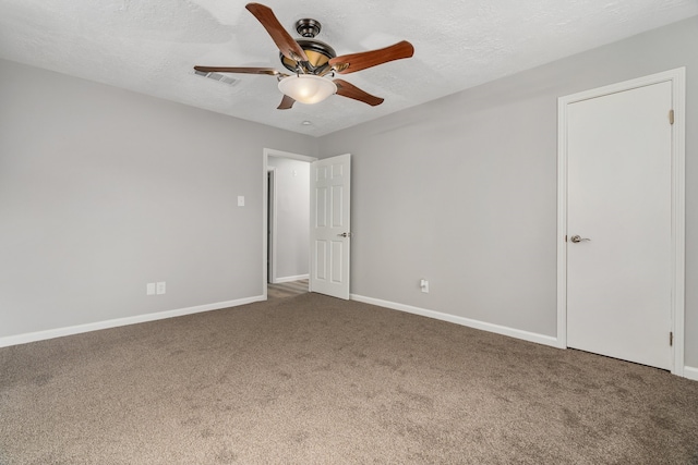 carpeted empty room featuring ceiling fan and a textured ceiling