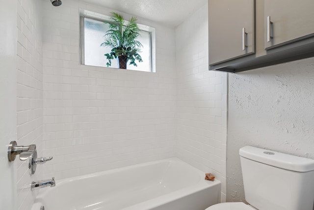 bathroom with tiled shower / bath combo, a textured ceiling, and toilet