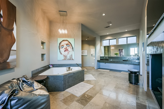 bathroom with tiled bath and a chandelier