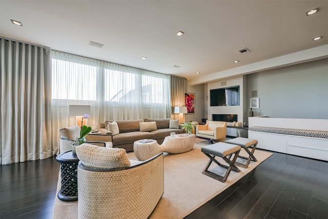 living room featuring dark hardwood / wood-style floors, a wall of windows, and a fireplace