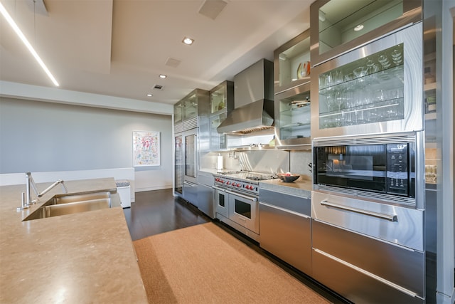 kitchen with tasteful backsplash, dark wood-type flooring, sink, black appliances, and wall chimney range hood