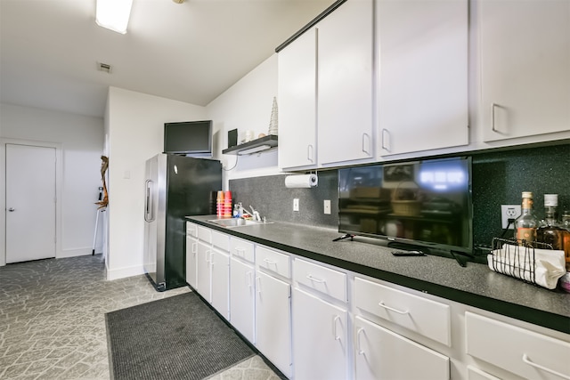 kitchen with decorative backsplash, white cabinetry, stainless steel refrigerator, and sink