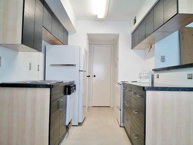 kitchen with a textured ceiling, electric range, and white fridge