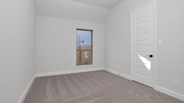 carpeted spare room featuring vaulted ceiling