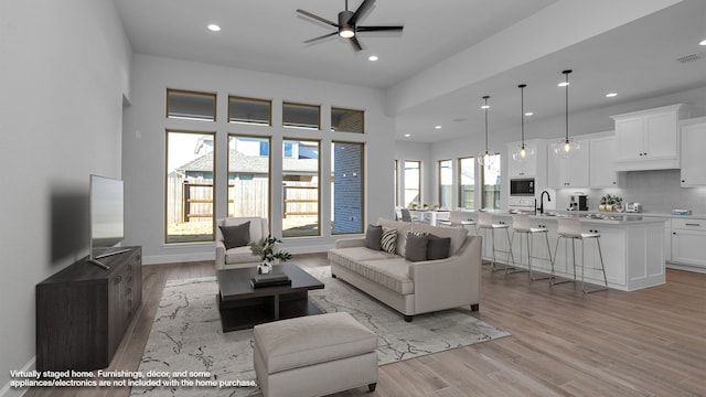 living room featuring ceiling fan, sink, and light hardwood / wood-style floors