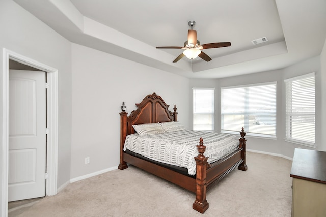 bedroom featuring ceiling fan, a raised ceiling, and light carpet