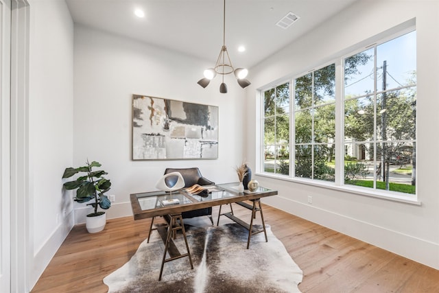 office area featuring a wealth of natural light, wood-type flooring, and a notable chandelier