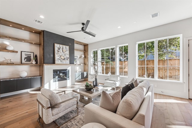 living room featuring ceiling fan, light hardwood / wood-style floors, and a fireplace