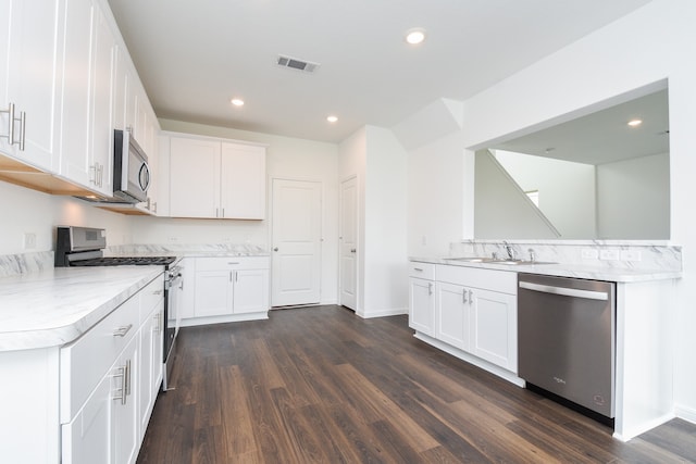 kitchen with white cabinets, sink, dark hardwood / wood-style floors, appliances with stainless steel finishes, and kitchen peninsula