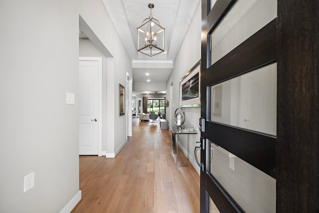 hall with a chandelier, light hardwood / wood-style floors, and crown molding