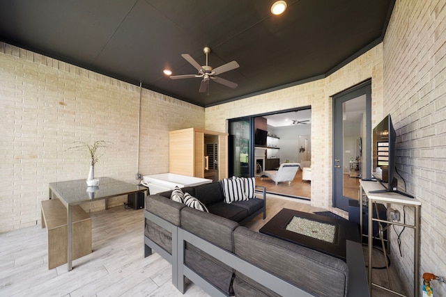 exterior space with ceiling fan, light hardwood / wood-style flooring, and brick wall