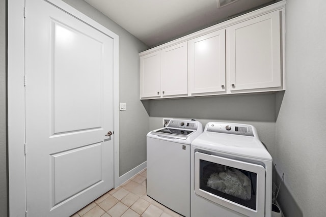 laundry area with washer and dryer, light tile patterned floors, and cabinets