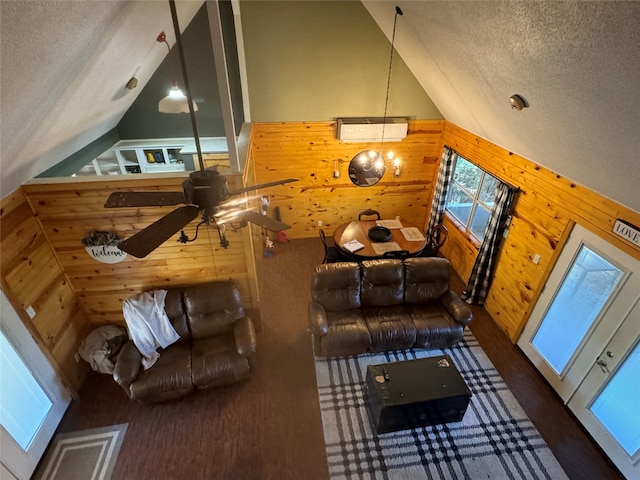 living room with wooden walls, high vaulted ceiling, a textured ceiling, and ceiling fan