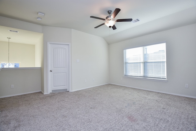 spare room featuring ceiling fan with notable chandelier, lofted ceiling, and light carpet