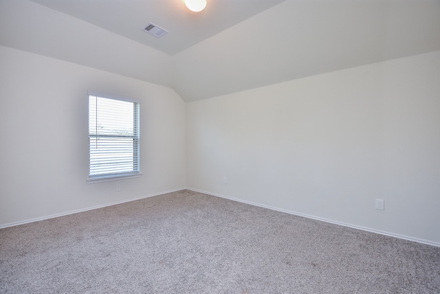 spare room with carpet flooring and vaulted ceiling